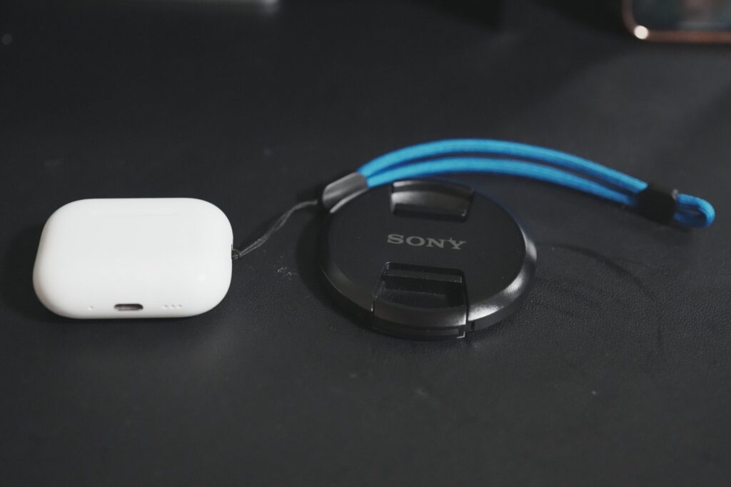 暗い机の上に置いた白いケースとレンズキャップ。ホワイトバランスはオート